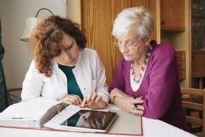 female Home Caregiver helps senior woman with paperwork